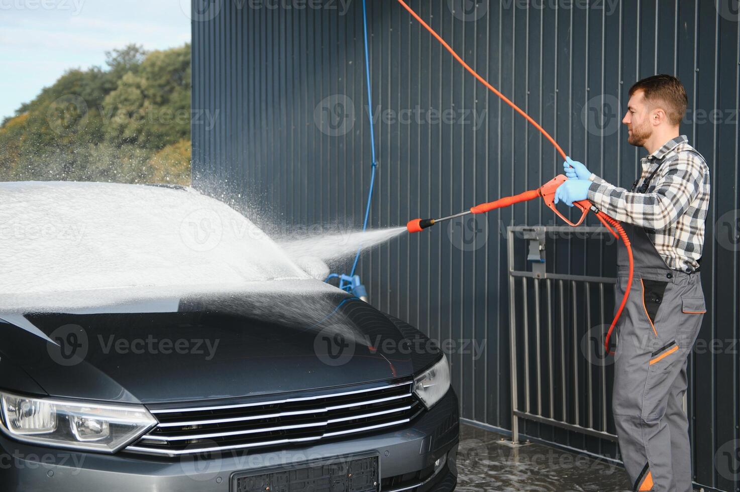 Man worker washing car service. Car wash cleaning station high pressure water. Employees clean a vehicle professionally photo