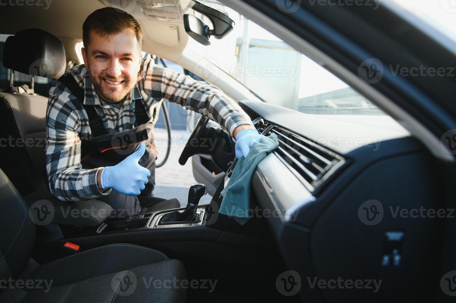 Feeling happy to be doing an excellent job at my job at the car wash. Portrait of a man while sitting inside a customer vehicle photo