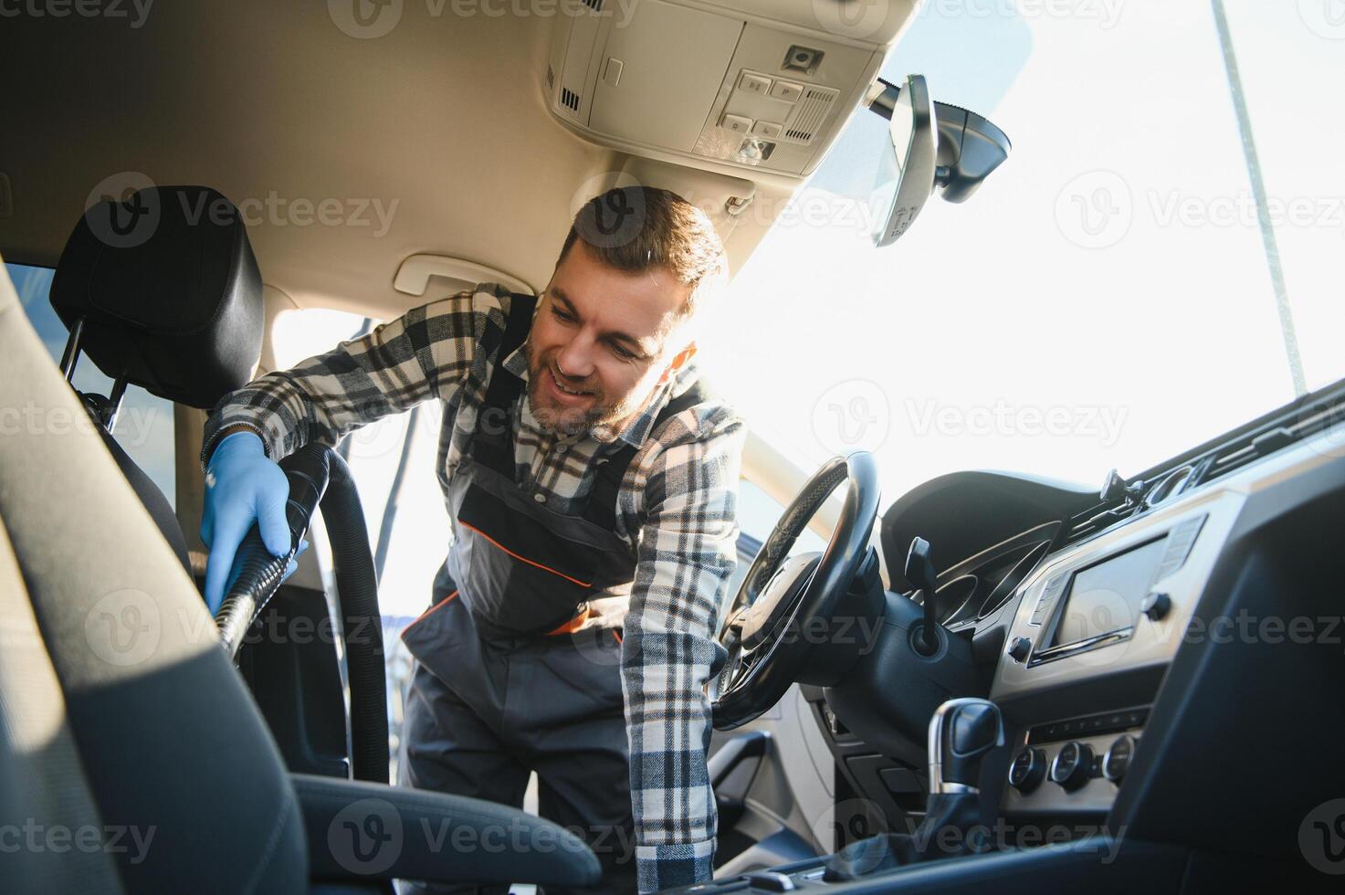 Feeling happy to be doing an excellent job at my job at the car wash. Portrait of a man while sitting inside a customer vehicle photo