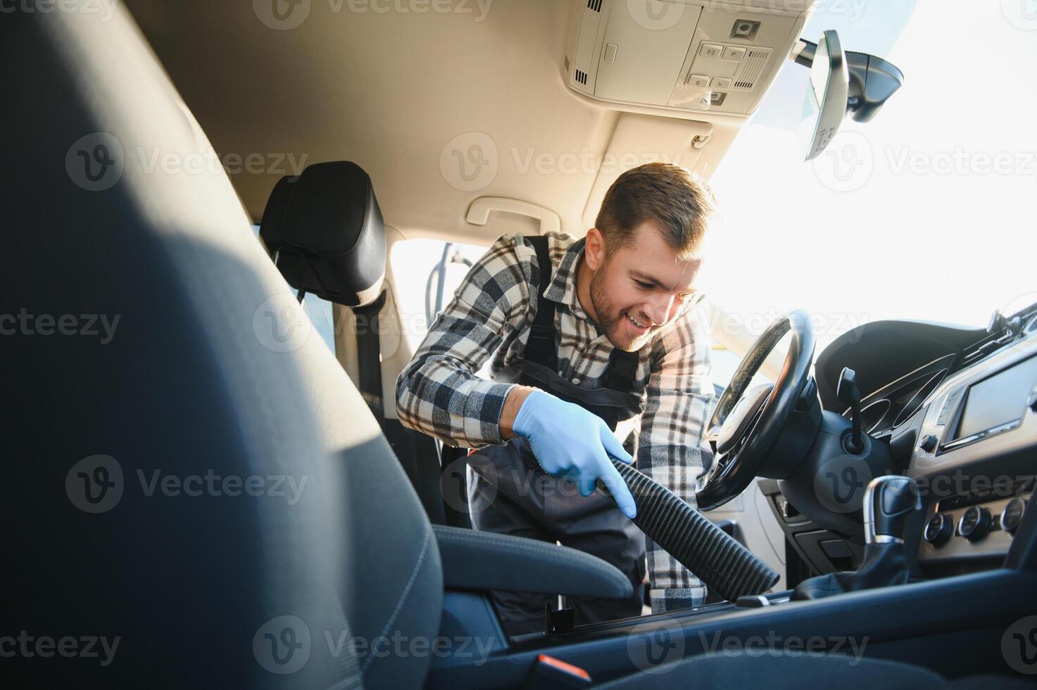Feeling happy to be doing an excellent job at my job at the car wash. Portrait of a man while sitting inside a customer vehicle photo
