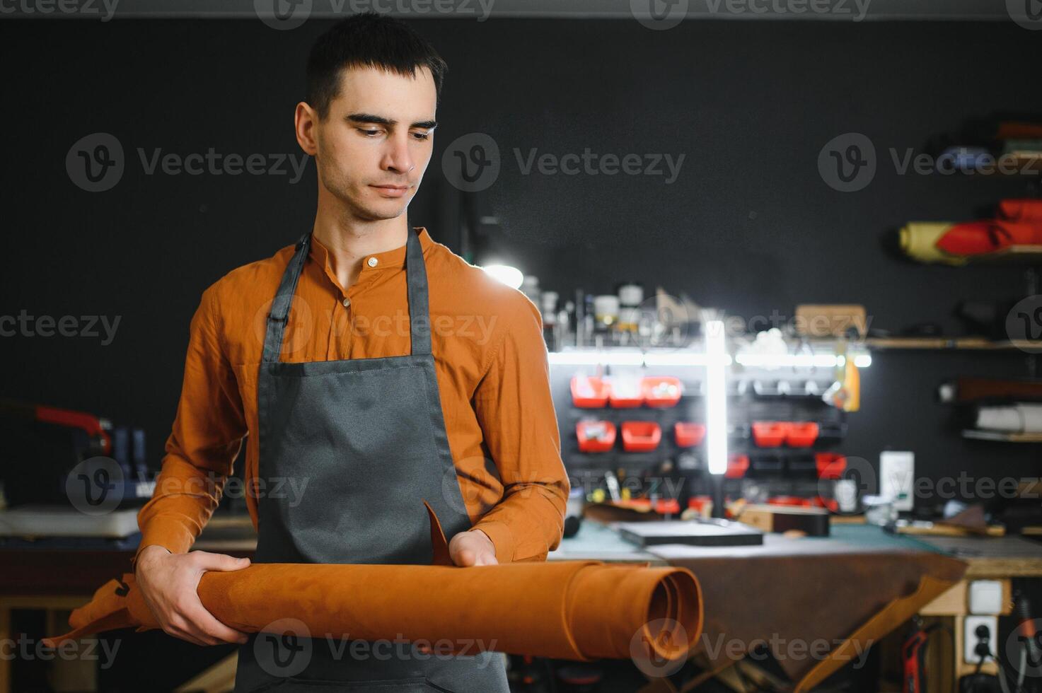 Tailor cobbler hold different rolls natural brown leather, working in workshop. Concept banner Industrial professional craftsman master photo