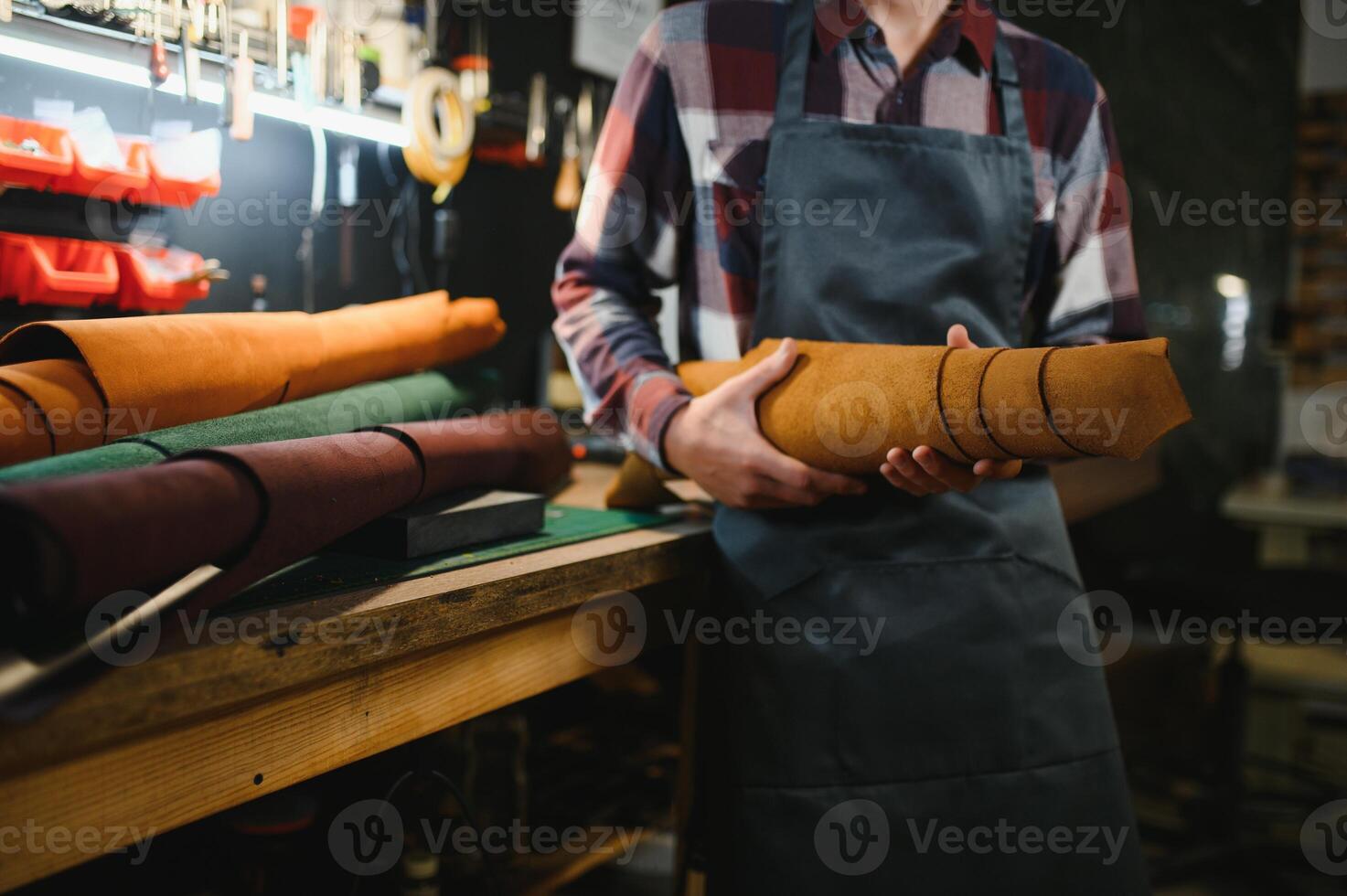 Tailor cobbler hold different rolls natural brown leather, working in workshop. Concept banner Industrial professional craftsman master photo