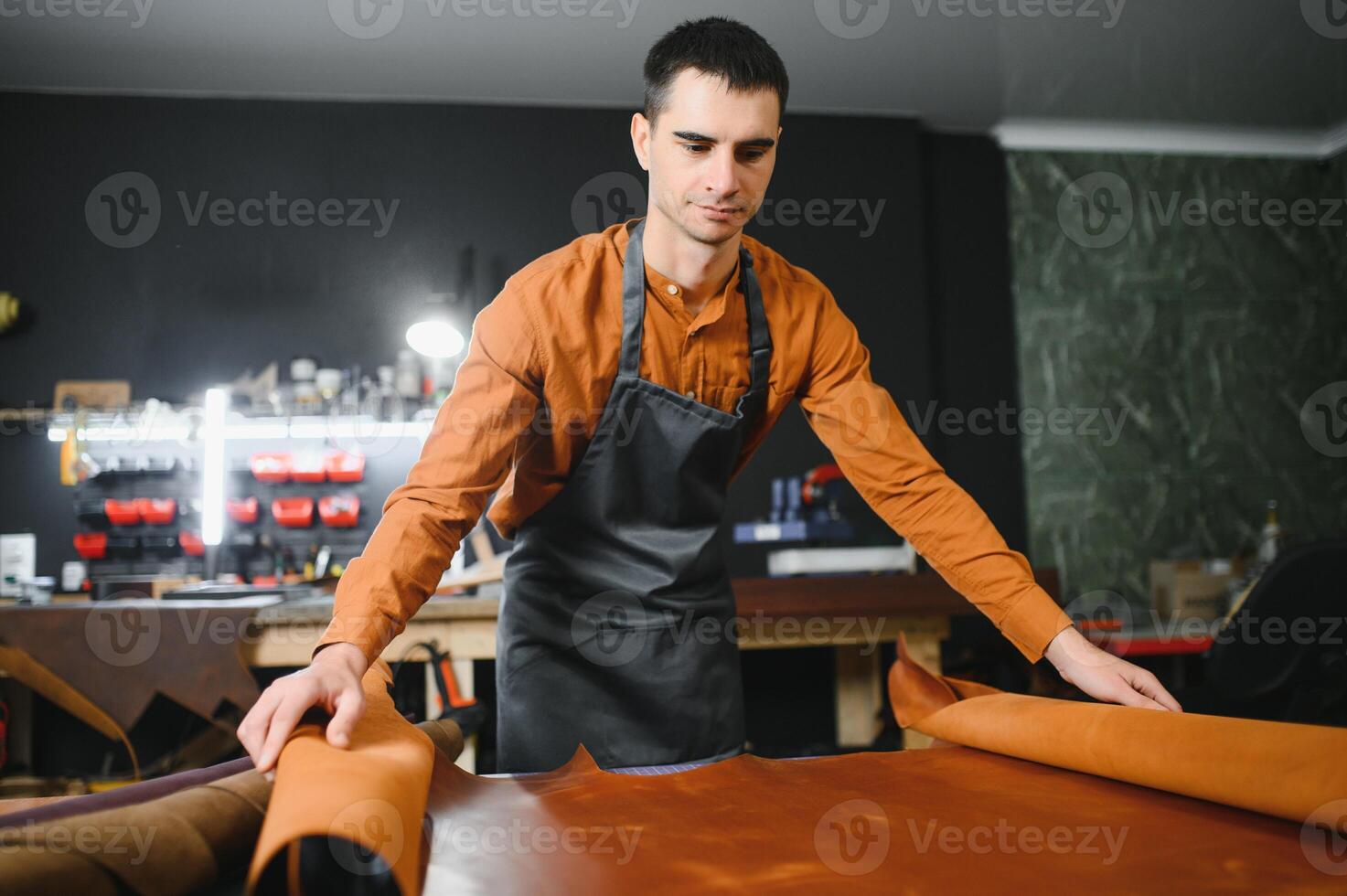 Tailor cobbler hold different rolls natural brown leather, working in workshop. Concept banner Industrial professional craftsman master photo