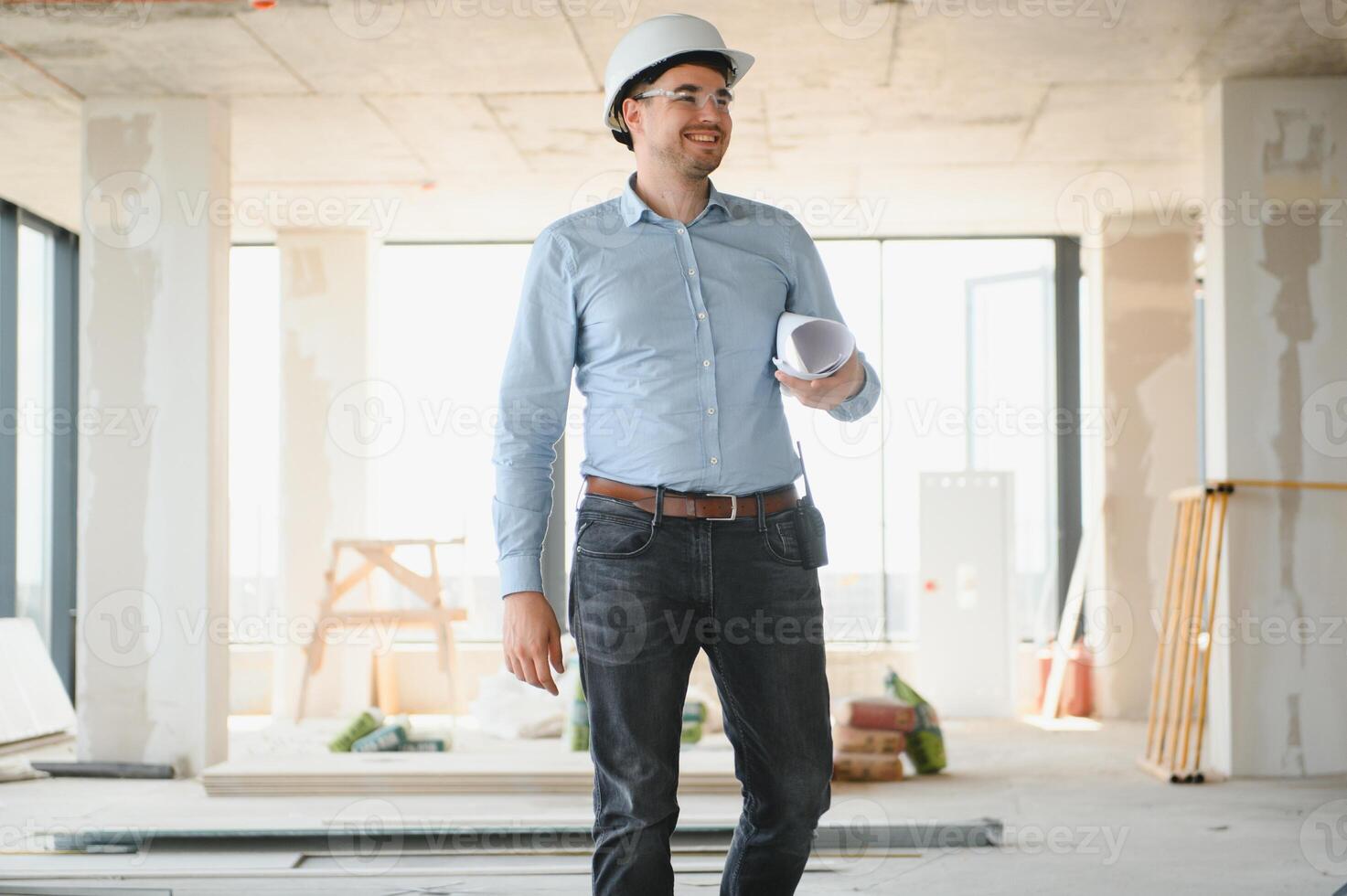 Portrait of an architect builder studying layout plan of the rooms, civil engineer working with documents on construction site photo