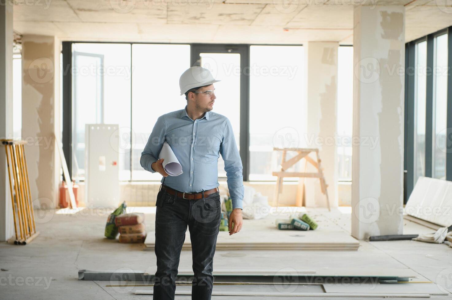 Portrait of an architect builder studying layout plan of the rooms, civil engineer working with documents on construction site photo