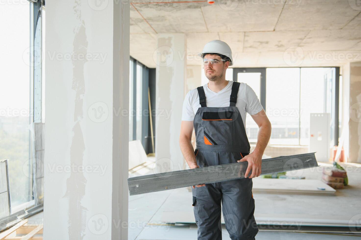 Builder in working uniform cutting metal profile with cutting machine at the construction site indoors photo