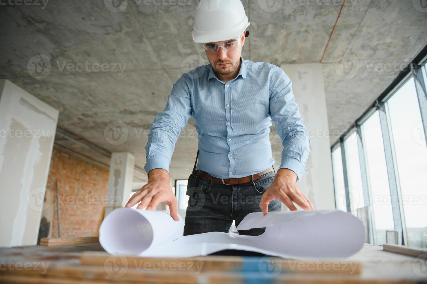 With plan in hands. Man in uniform is working on the construction site photo