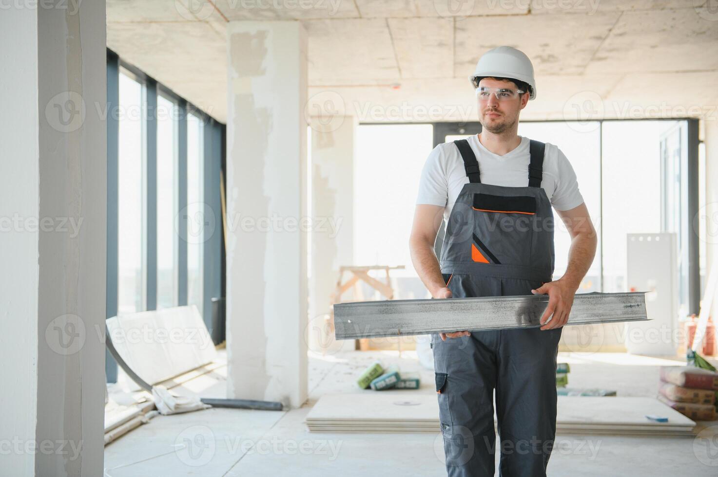 Builder in working uniform cutting metal profile with cutting machine at the construction site indoors photo