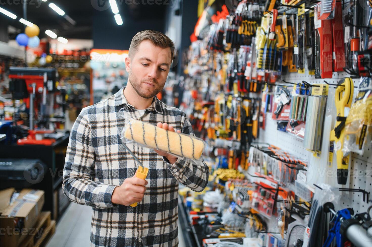 A male customer in a modern hardware store chooses a paint roller photo