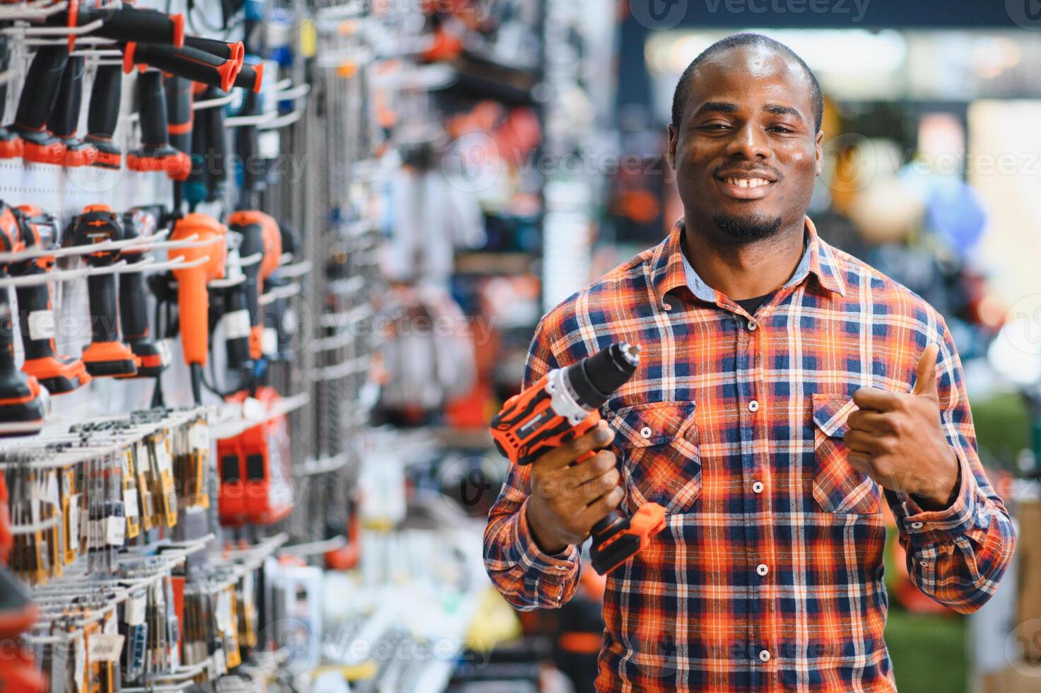 African americam man buying modern electric drill while standing in tool. Hardware construction site objects concept photo