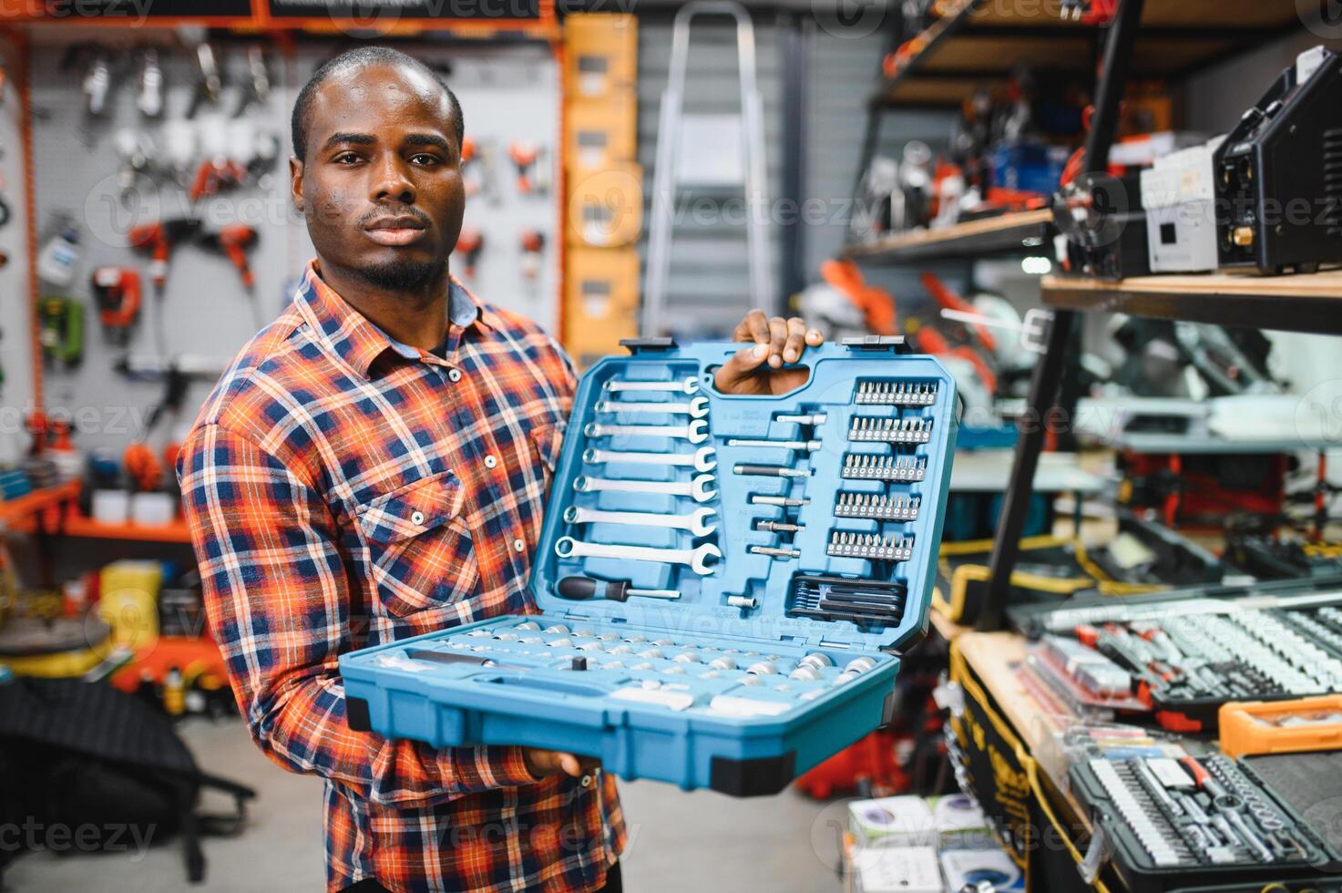 African american male buyer chooses a toolbox in a hardware store. A large selection of tools photo