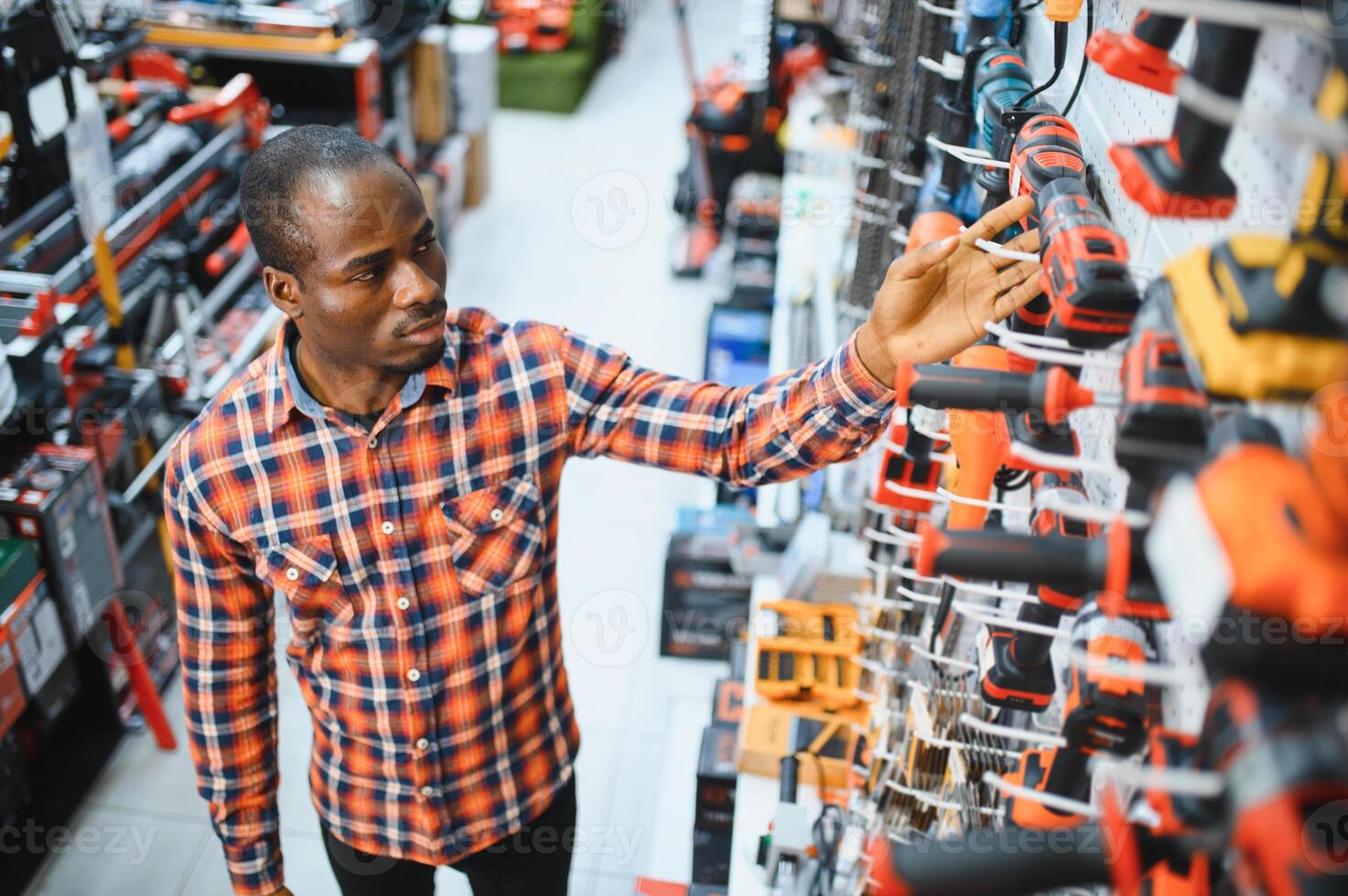African americam man buying modern electric drill while standing in tool. Hardware construction site objects concept photo