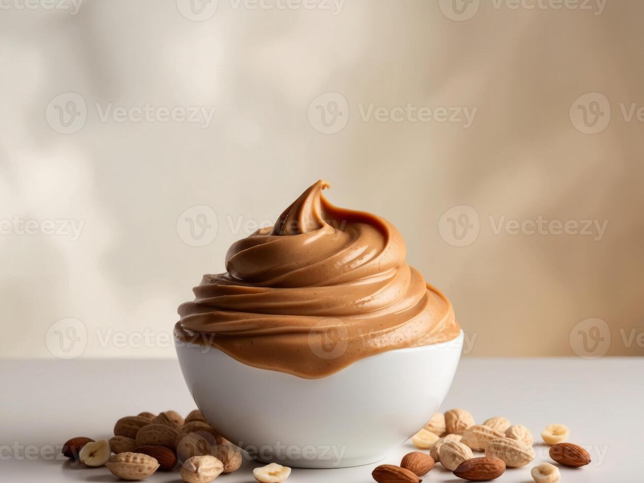 Smooth peanut butter in a white bowl surrounded by scattered peanuts and almonds on a light background. photo