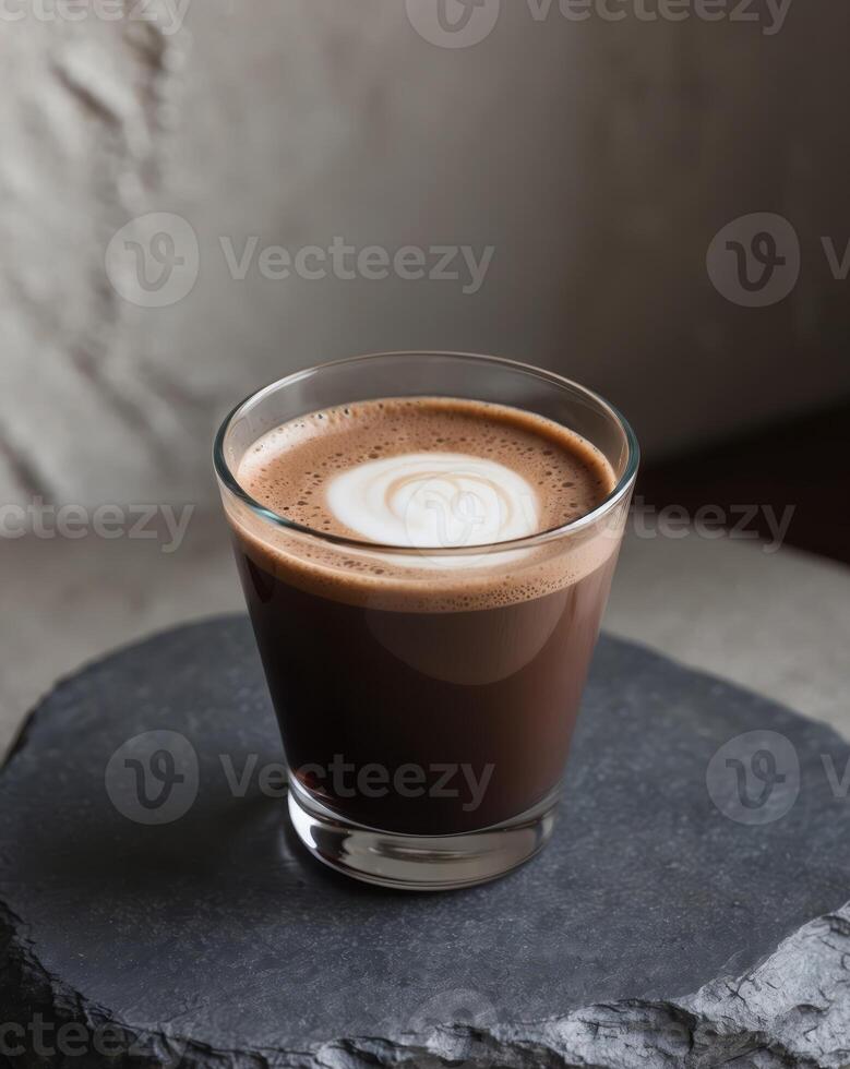 Glass of iced chocolate coffee with creamy froth served on dark textured background photo