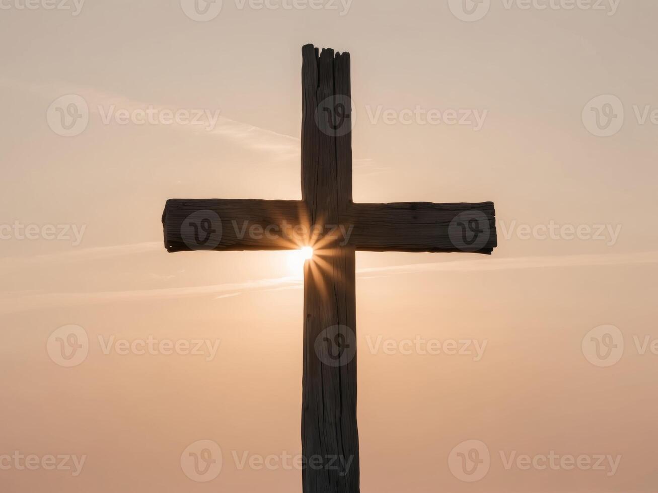 Sunlight shine through silhouette of big wooden Christian cross on open field during sunset. photo