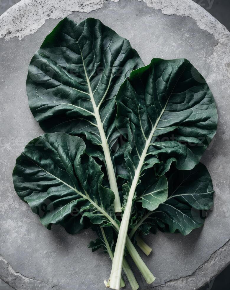 Freshly cut collard greens on stone surface showcasing broad dark green leaves with visible veins photo
