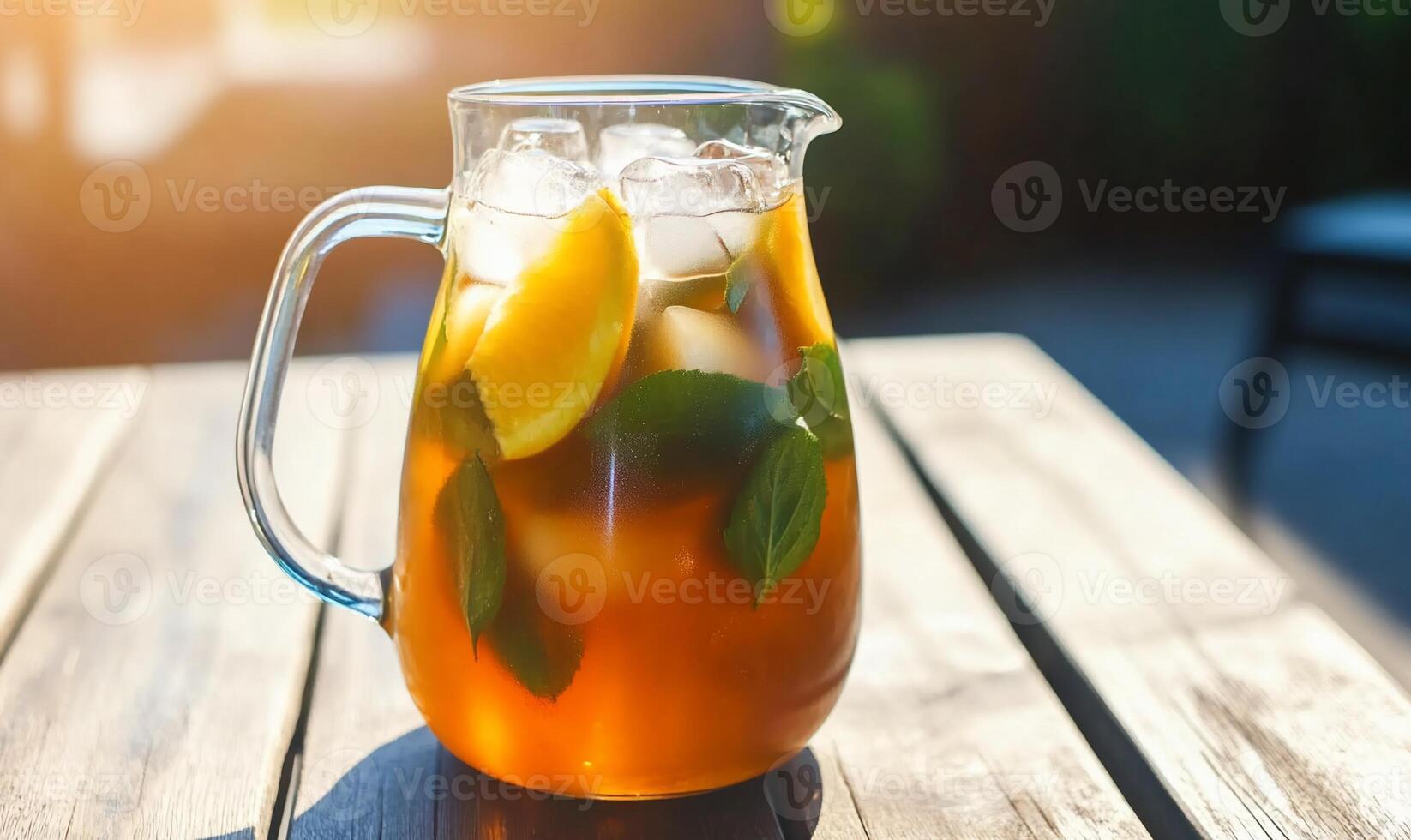 A refreshing pitcher of iced tea with lemon and mint on a sunny table. photo