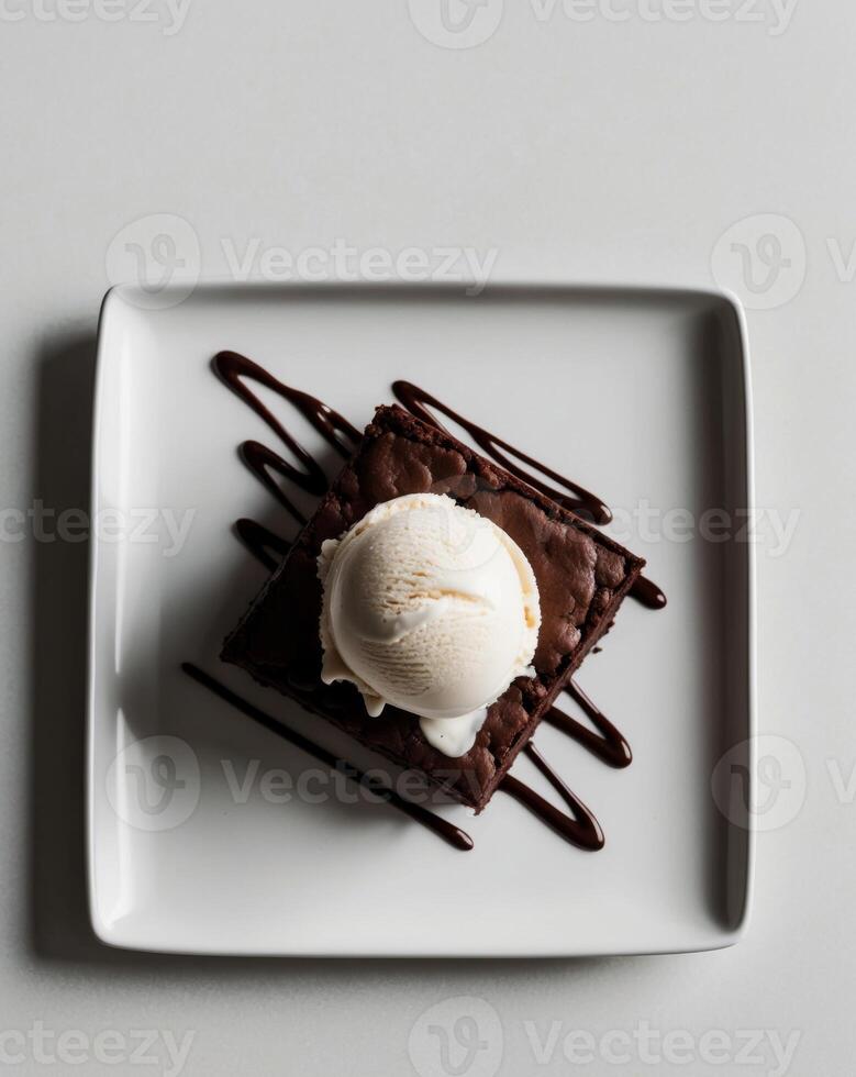 Overhead view artisanal dessert platter square white plates chocolate brownie vanilla ice cream scoop chocolate sauce drizzle. photo