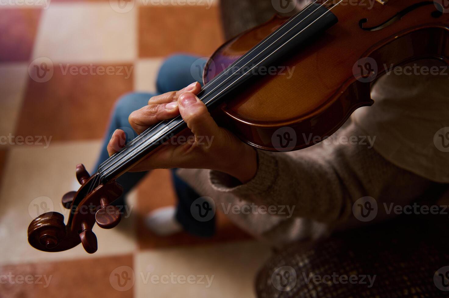 Close-up of hands skillfully playing a violin on a checkered floor photo