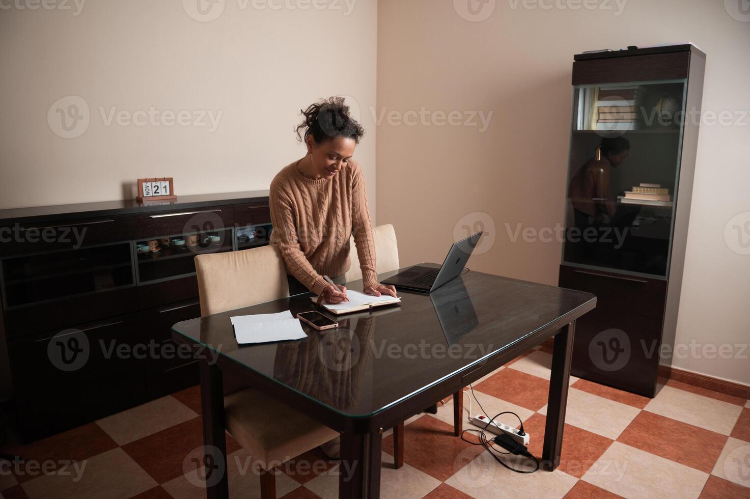 Woman working from home at a desk with a laptop and notes photo