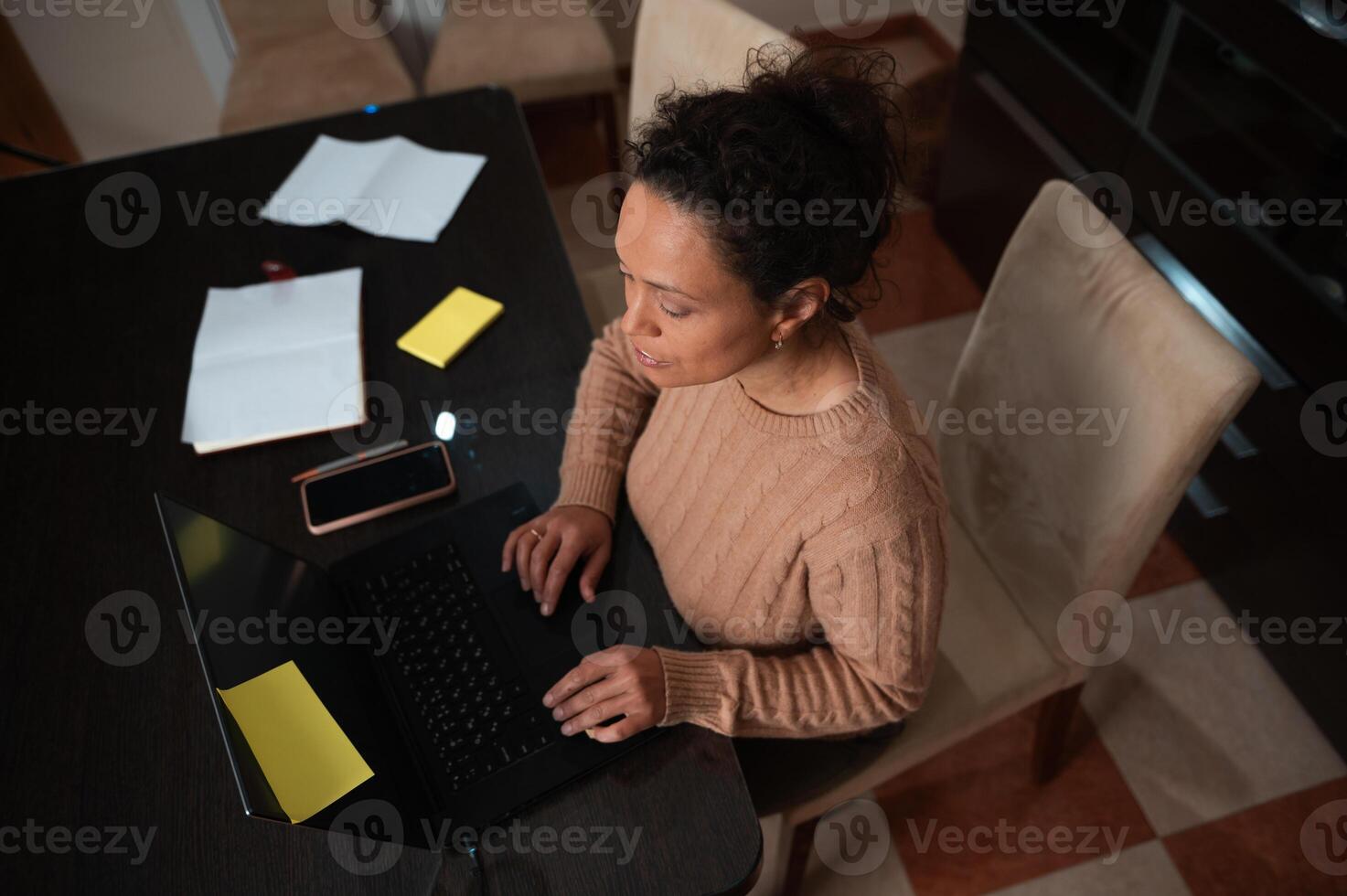 Woman working from home using a laptop at a wooden table photo