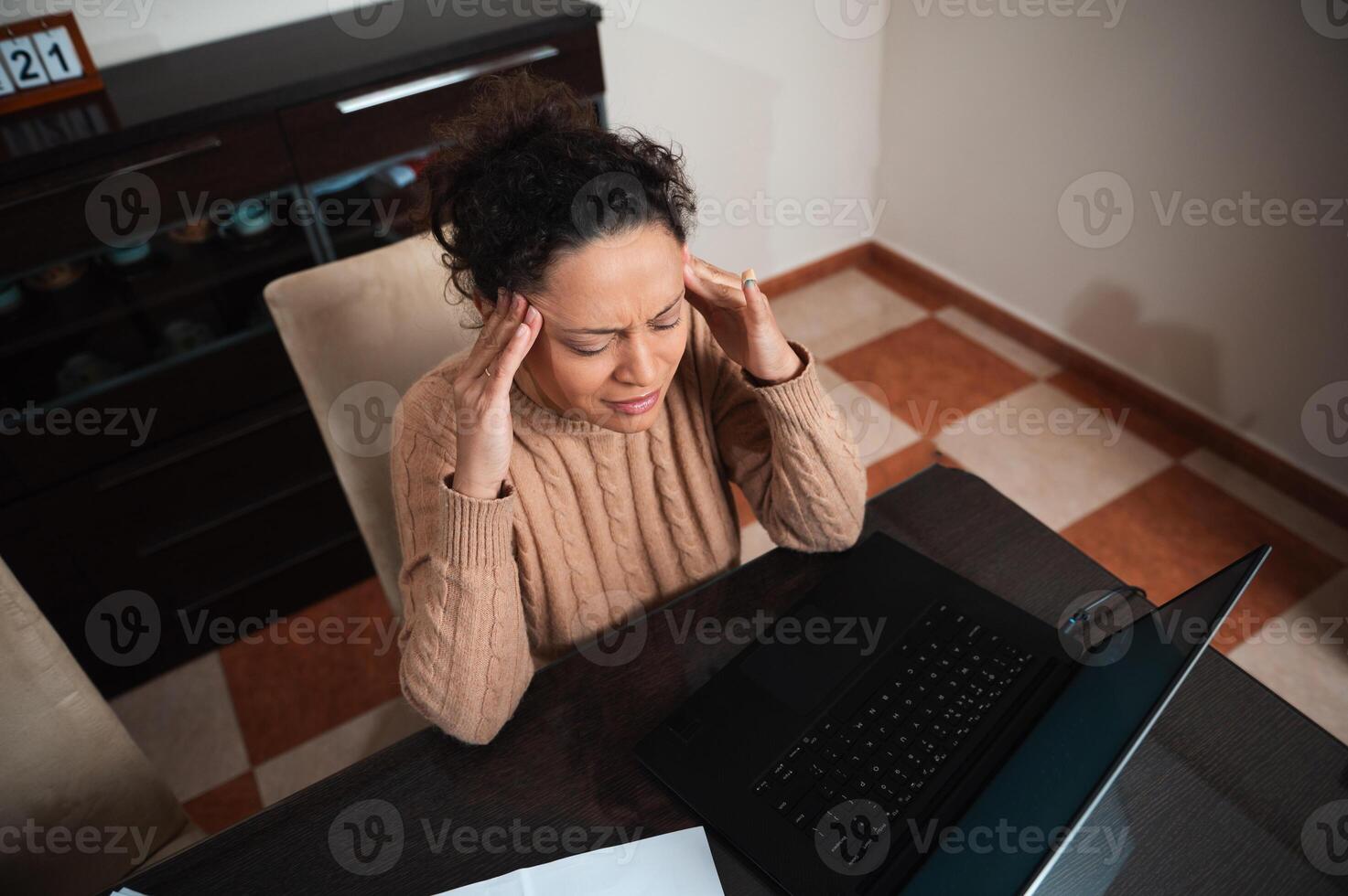 Woman experiencing stress while working on a laptop at home photo