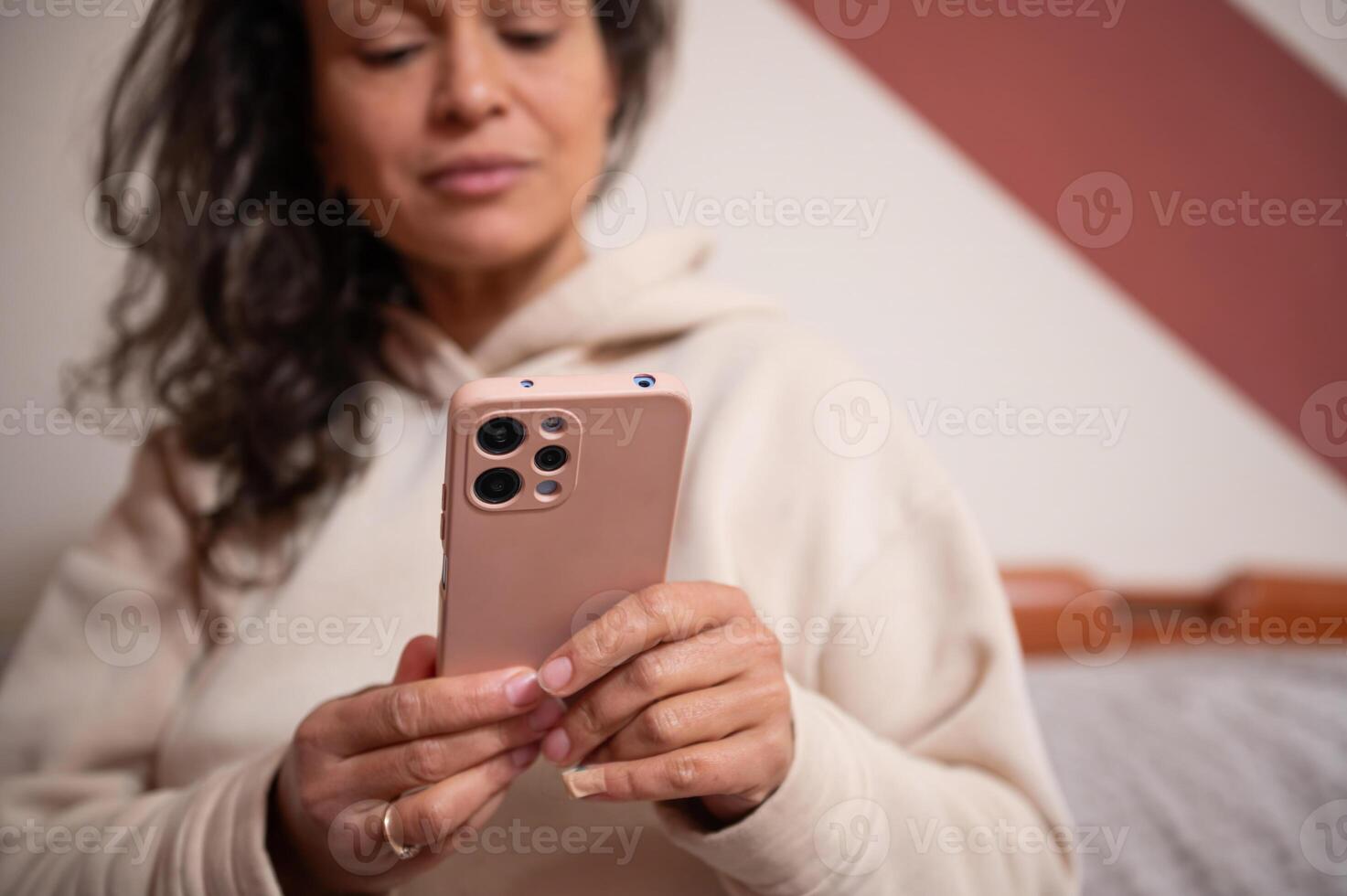 Woman using smartphone while relaxing indoors in casual clothing photo