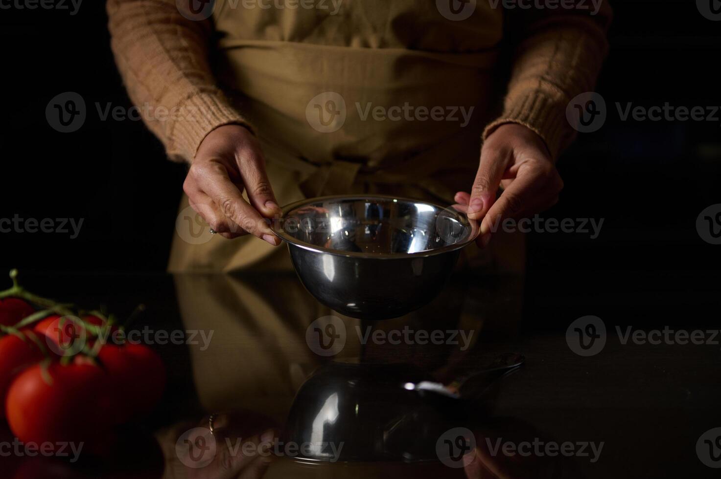 Hands holding a mixing bowl with fresh tomatoes on the counter photo