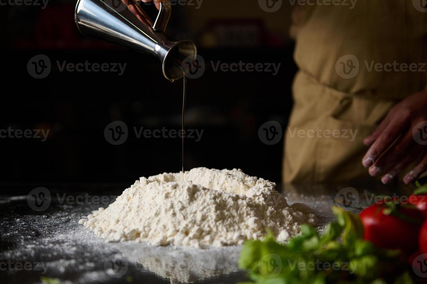 Chef pouring olive oil into flour for homemade pizza dough photo