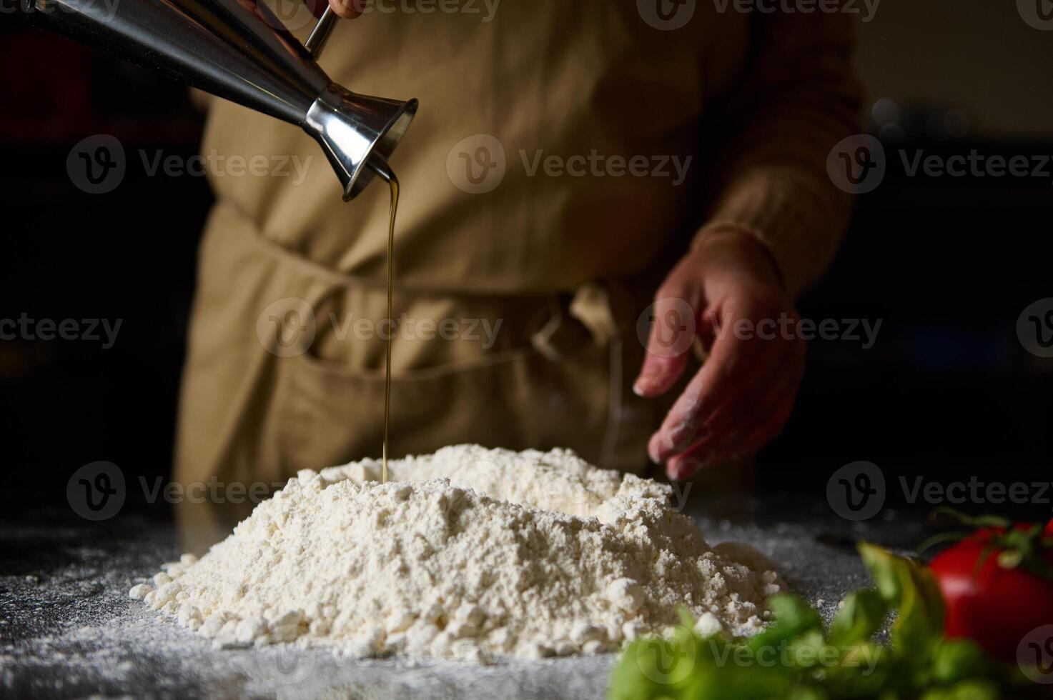 Chef pouring oil into flour for making fresh homemade dough photo