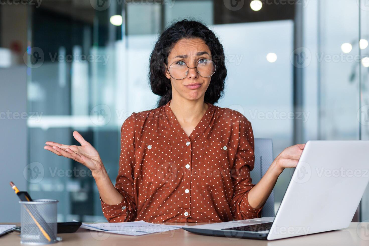Frustrated and tired business woman looking at camera, Hispanic woman unhappy with work result, working inside office using laptop at work. photo