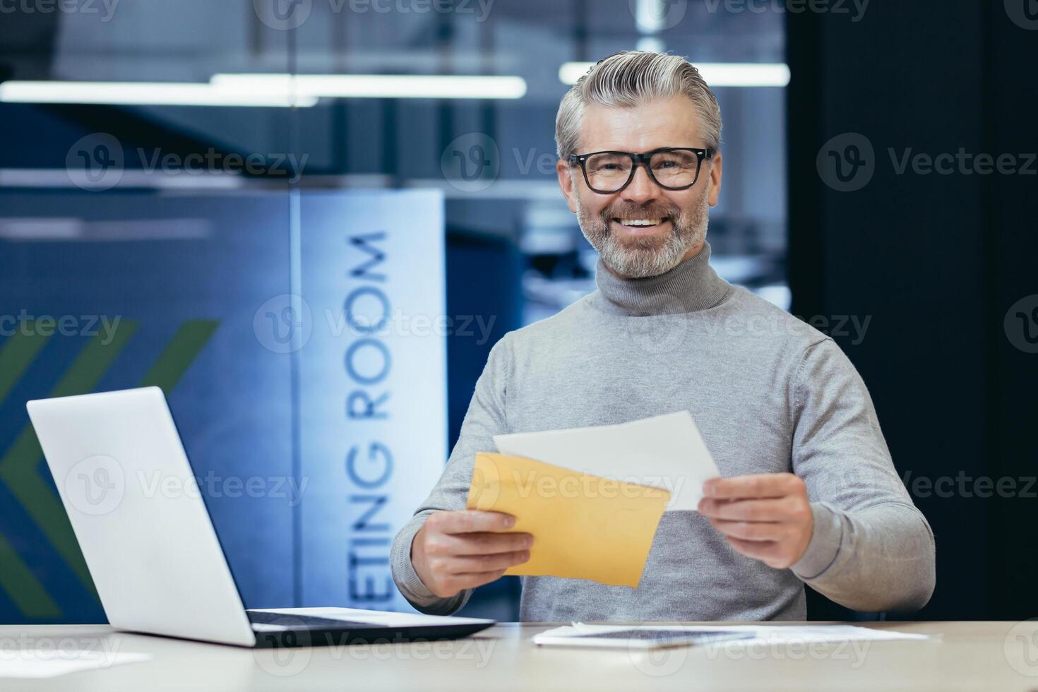 Portrait of successful mature financier, senior gray haired businessman smiling and looking at camera at workplace, boss received notification mail letter, with good news, man working inside office. photo