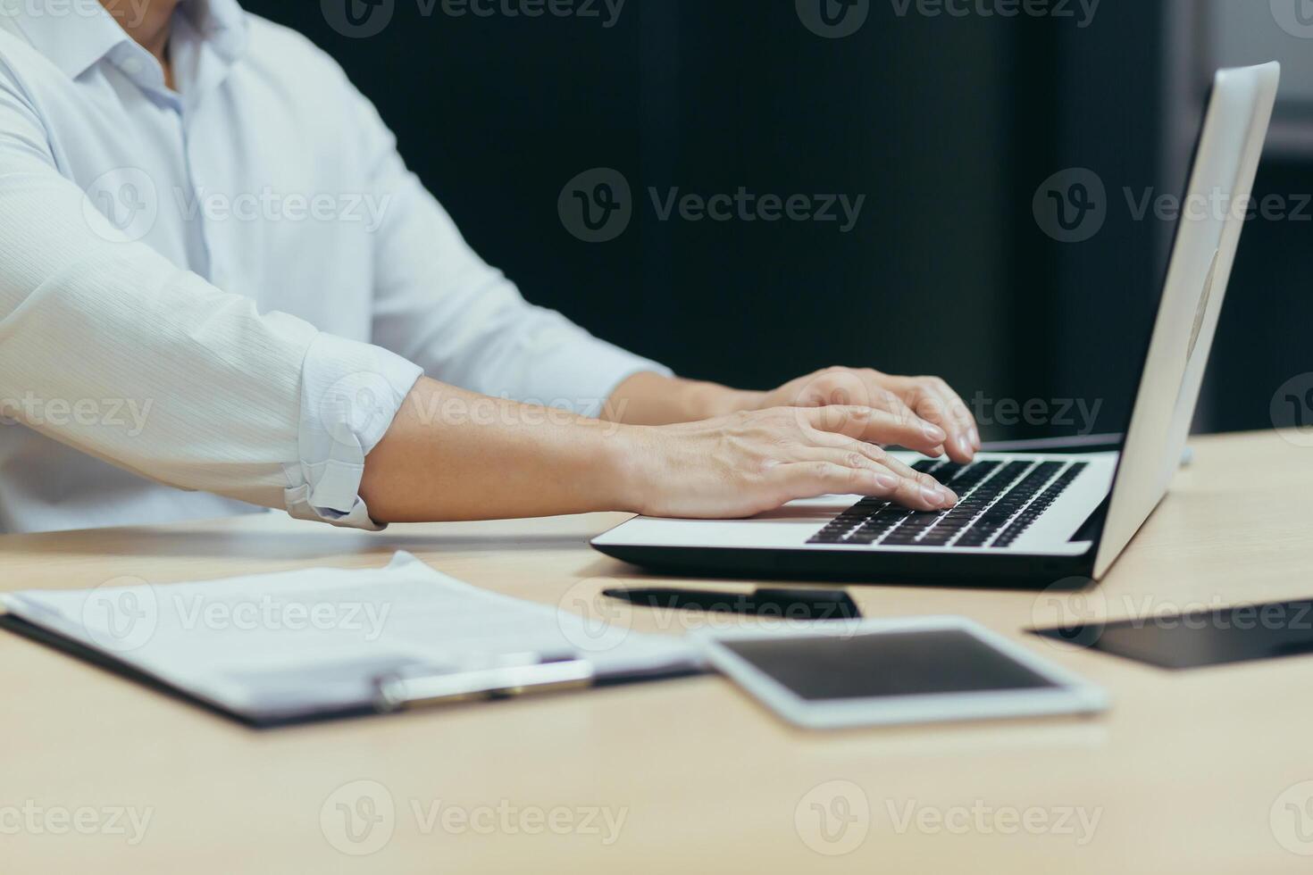 Close-up photo of a business man's hands working and typing on a laptop keyboard, a manager working in the office at a table.