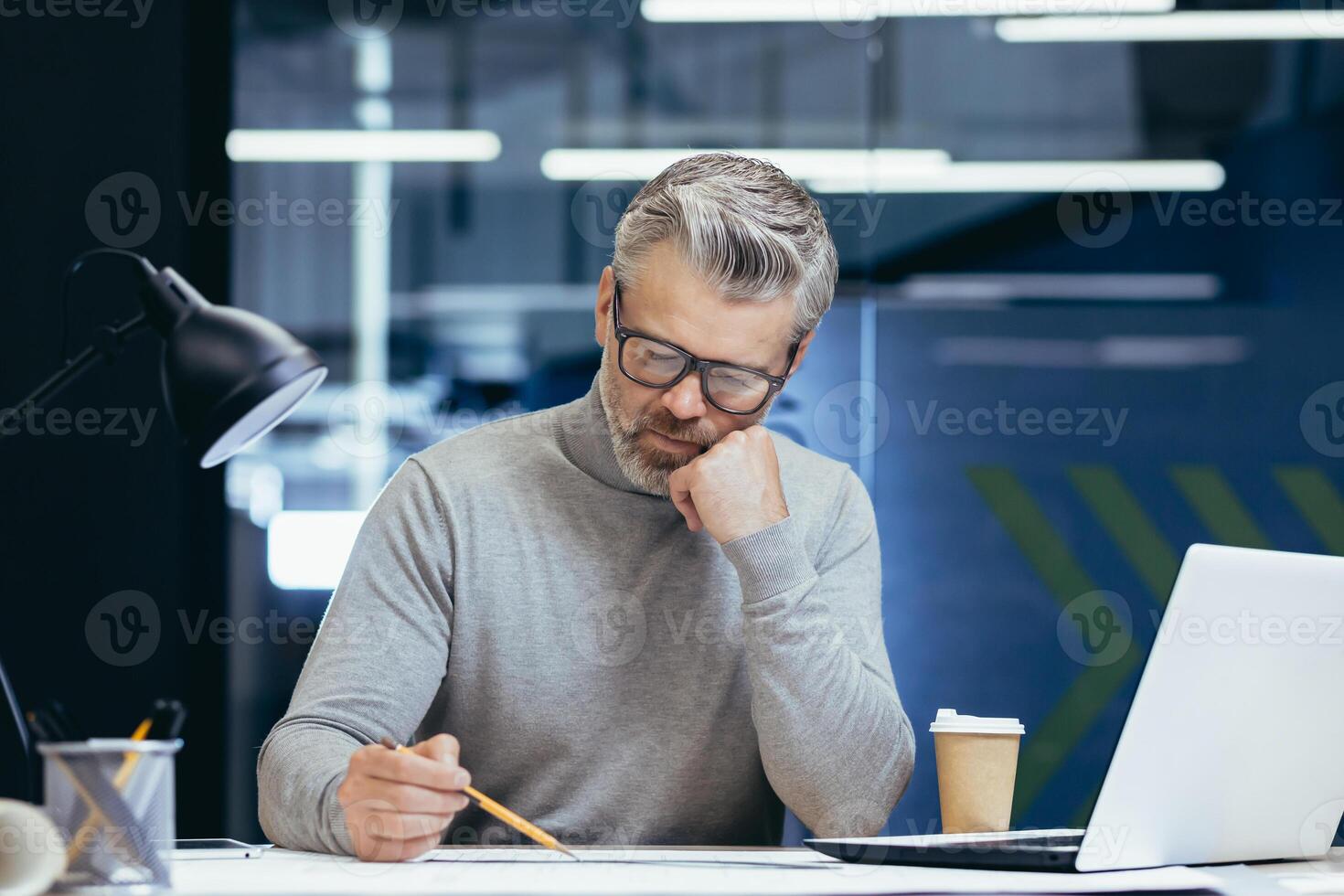Serious thinking architect designer working on blueprint, mature man working inside office engineer designing on whatman. photo