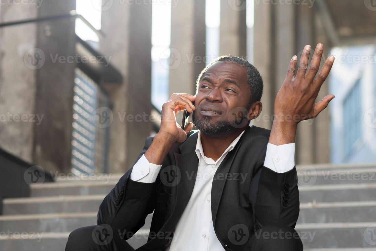 Losing the case in court. Upset scared black man sitting on steps outside courthouse. Talking on the phone. Divorce, alimony, custody, bankruptcy, deportation. photo