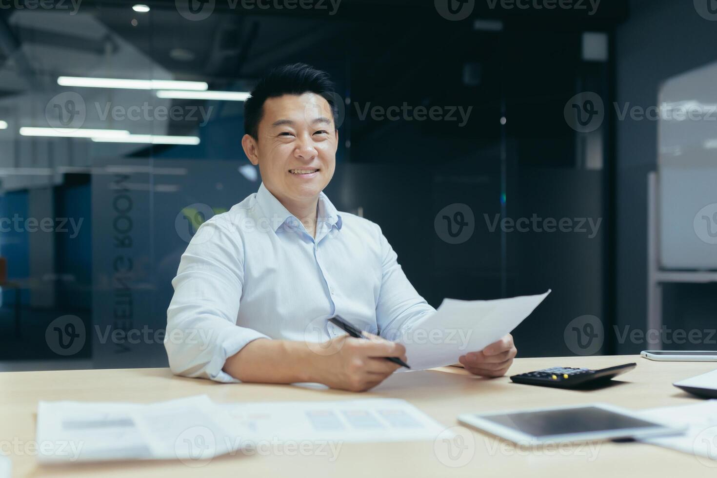 Portrait of successful Asian businessman, man smiling and looking at camera, broker doing paperwork photo