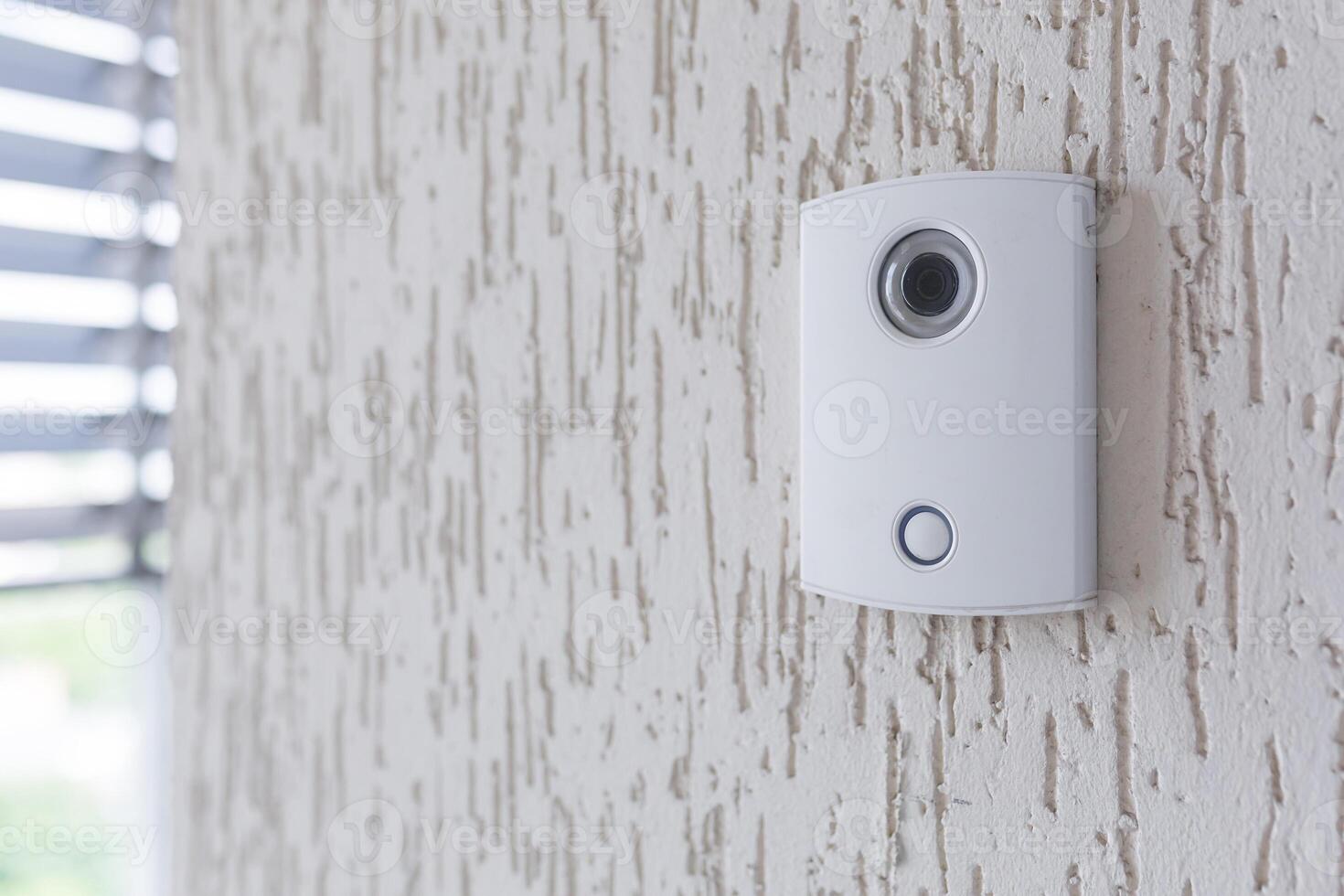A white incoming electronic doorbell with a camera on the wall of the building, office. photo