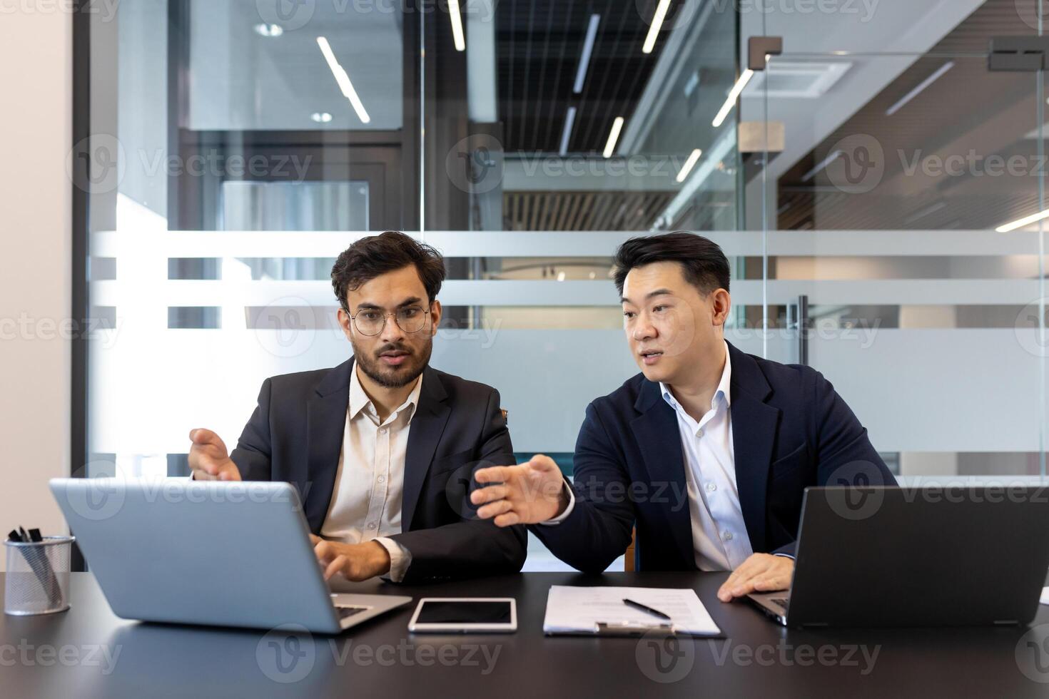 Business professionals having a collaborative discussion in modern office, utilizing laptop and smartphone technology. Teamwork and strategy emphasized in meeting. photo