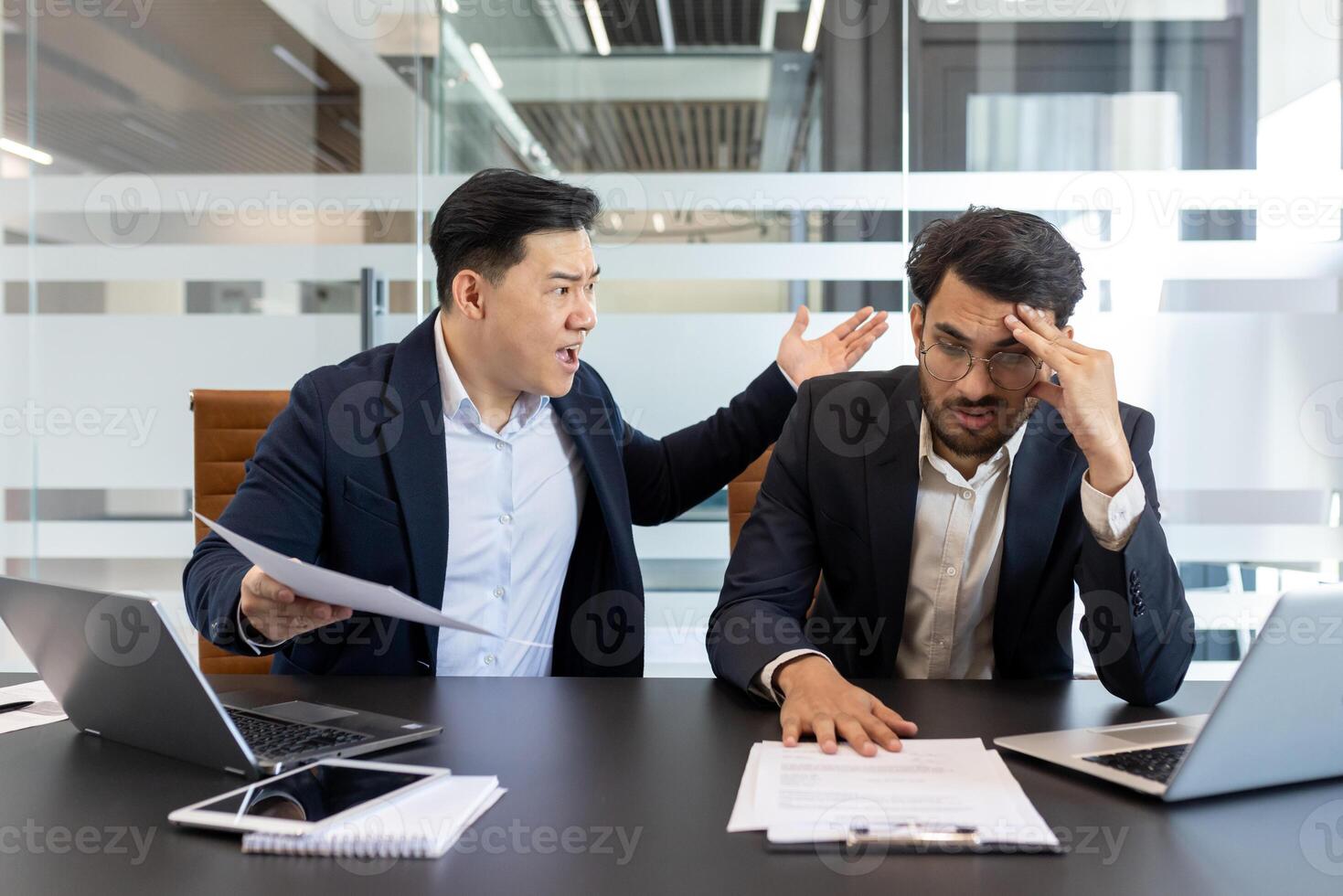 Angry colleague yelling at a stressed employee in a modern office setting. This scene captures workplace conflict, frustration, and pressure as they engage in a heated discussion over paperwork. photo