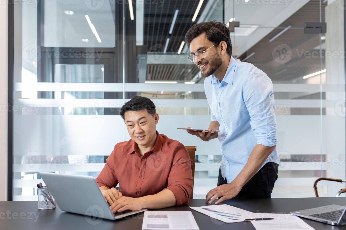 Team working on business project in office. Colleagues using laptop and smartphone for collaborative tasks, reviewing documents, engaging with technology for efficient workflow. photo