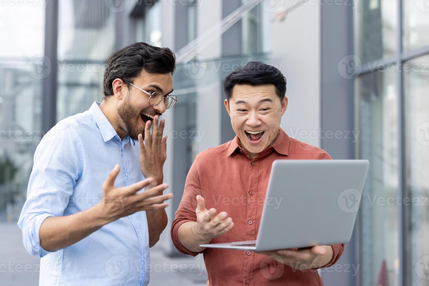 Two ecstatic colleagues celebrate a surprising success while looking at a laptop screen. Their joyous expressions and the laptop highlight a moment of achievement and teamwork. photo