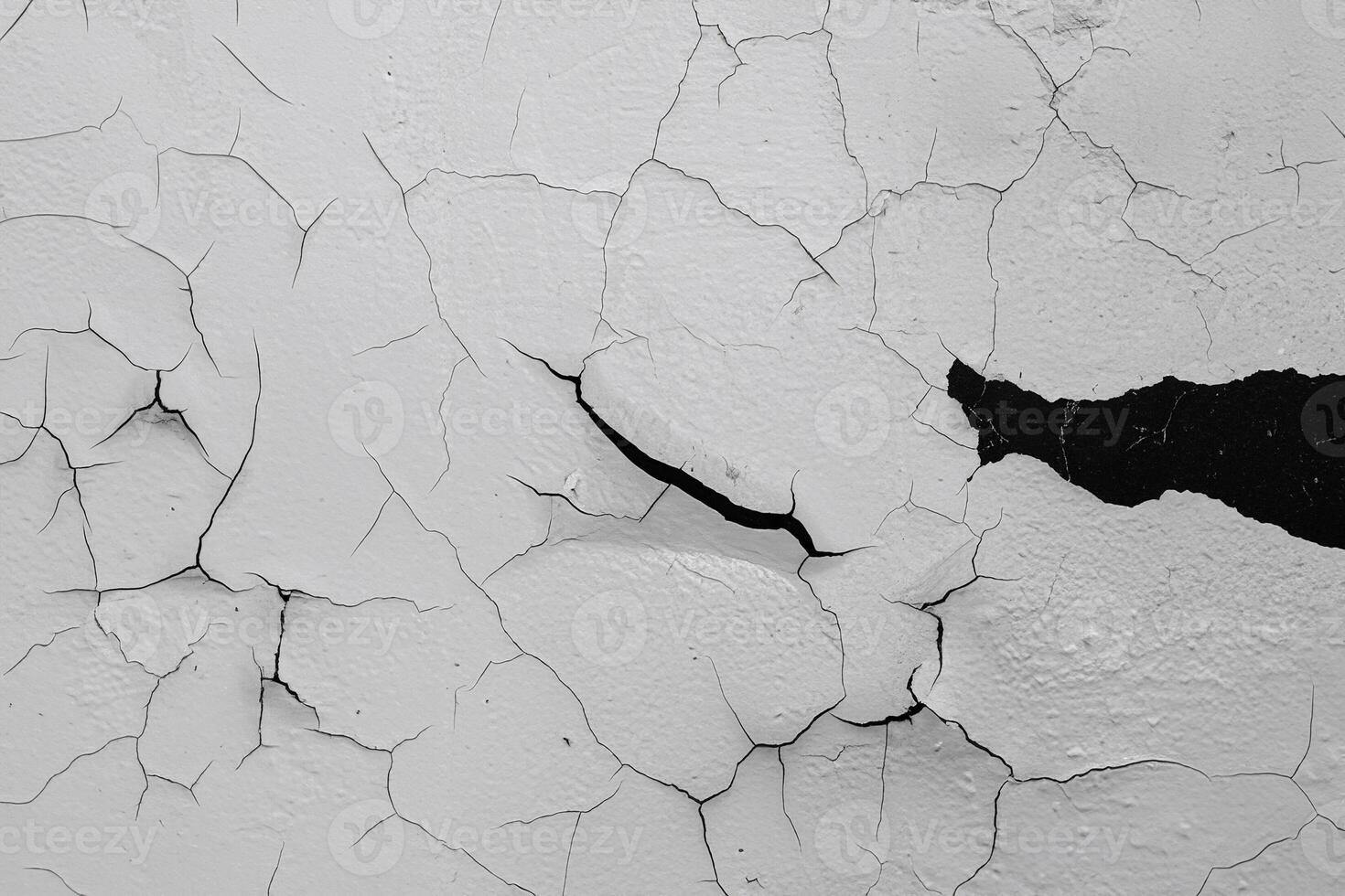 Close-up texture of a cracked white painted wall with visible peeling and cracks, ideal for backgrounds. photo