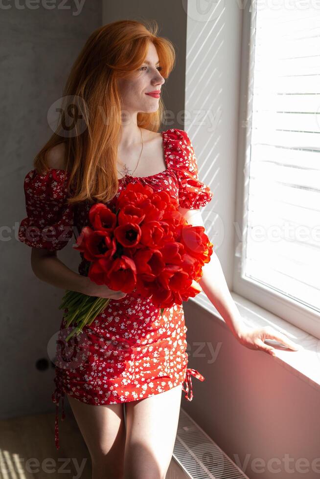Young happy woman with a bouquet of red lulips. photo