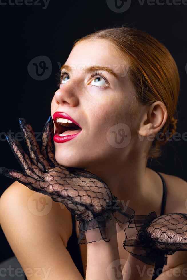 A young redhear girl with clean skin wearing black gloves. Beauty portrait of a woman photo