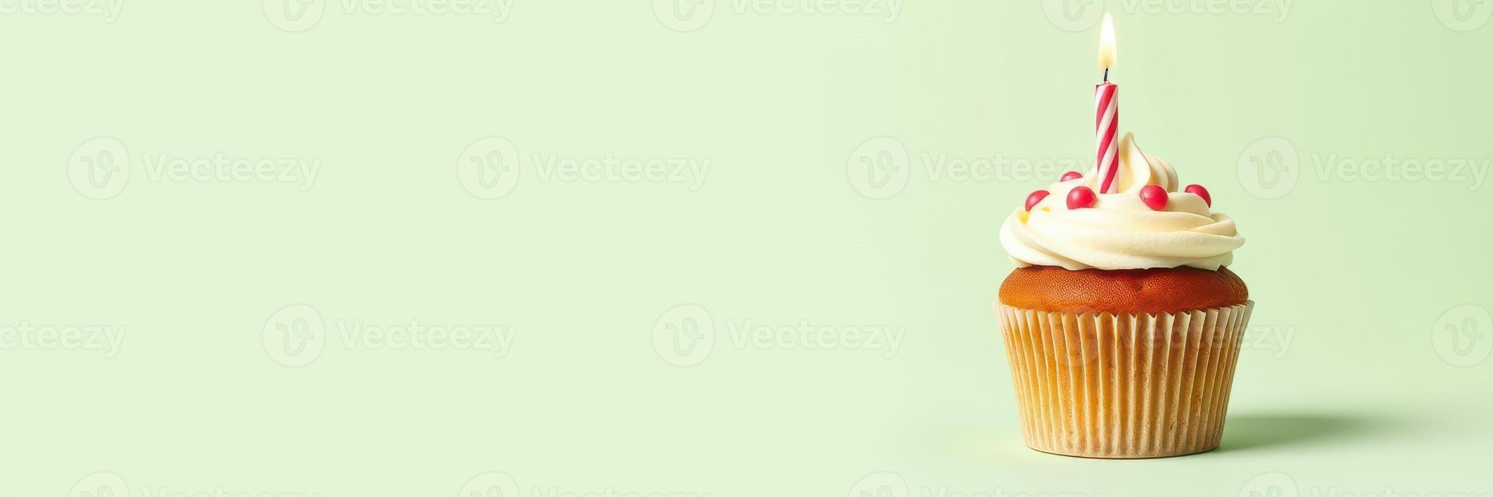Colorful cupcake with white frosting and a candle stands on a green background for a birthday celebration photo