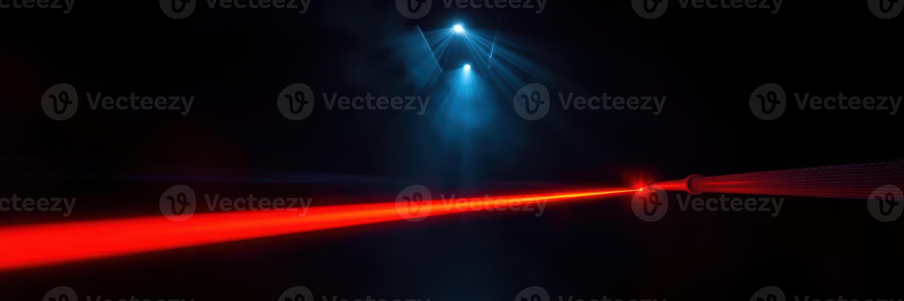Vibrant red laser cutting through darkness with blue spotlights illuminating the surrounding space during a nighttime event photo
