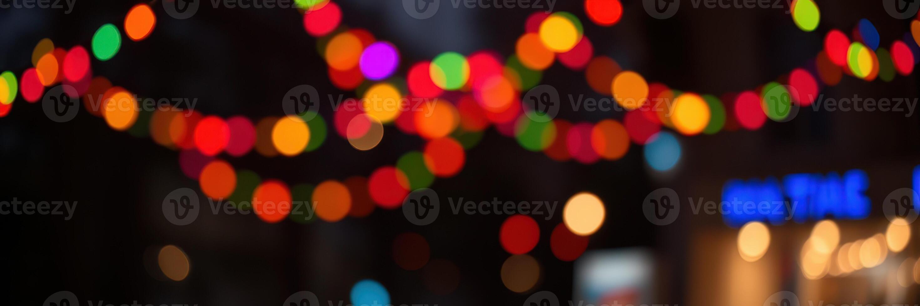 Colorful string lights illuminate a festive street during evening celebrations in a vibrant urban area photo