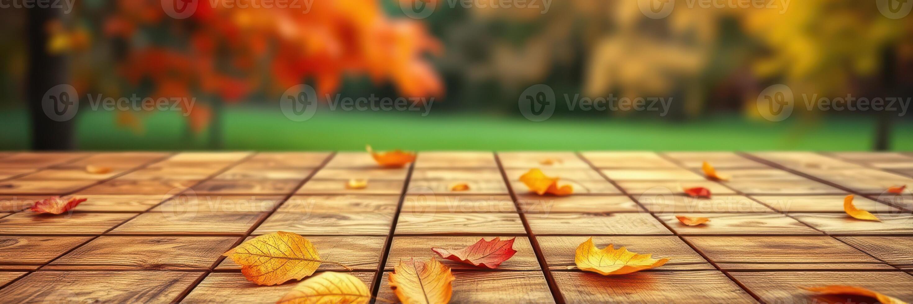 Colorful autumn leaves scattered on wooden deck with vibrant trees in the background creating a serene outdoor atmosphere photo