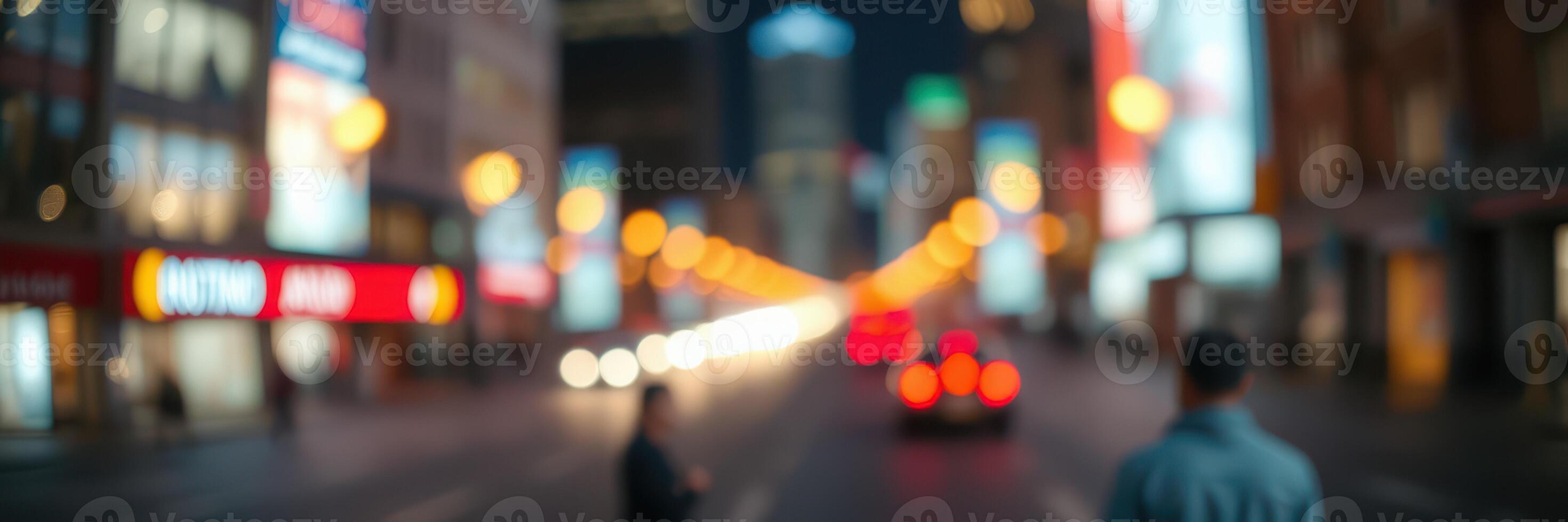 City street lights illuminate a bustling urban environment at night with blurred figures and vehicles in motion photo