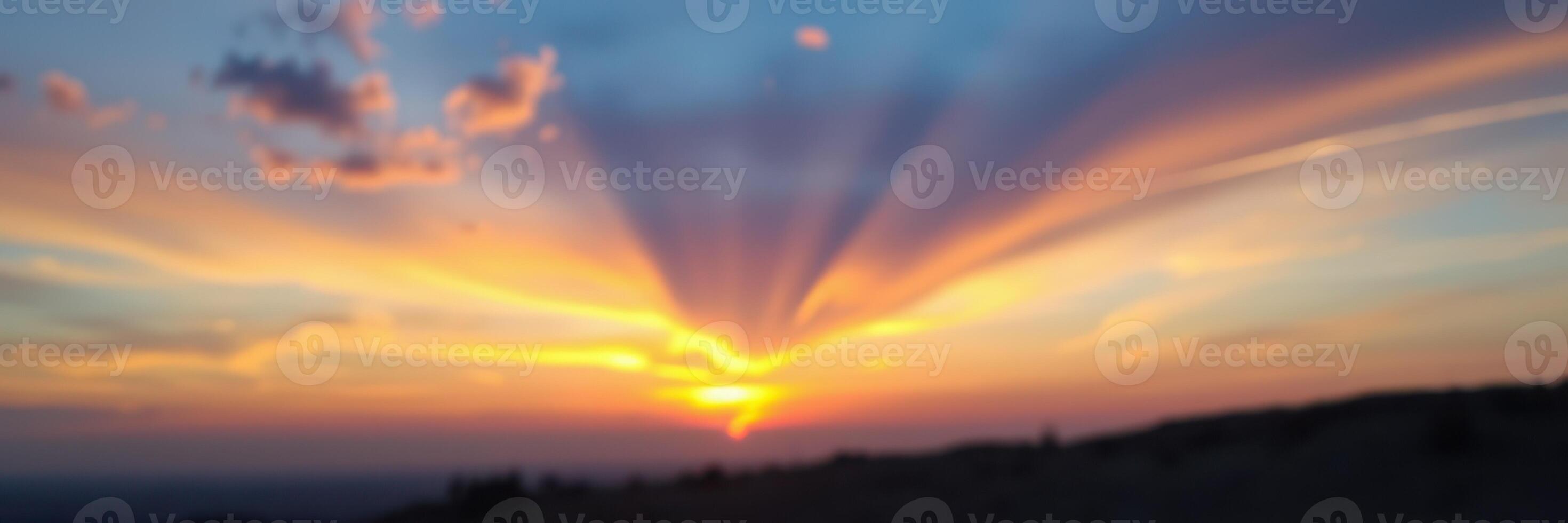 Colorful sunset displaying vibrant rays over the horizon in a serene landscape during evening hours photo